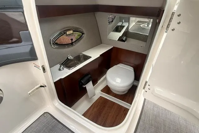 Slide: The Image of 2019 Chaparral 277 SSX boat bathroom with sink, toilet, and wood accents. - 13