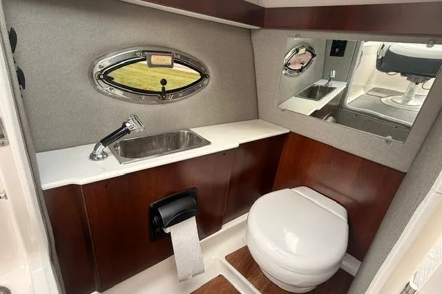 Slide: The Image of 2019 Chaparral 277 SSX boat bathroom with sink, toilet, and porthole window. - 14