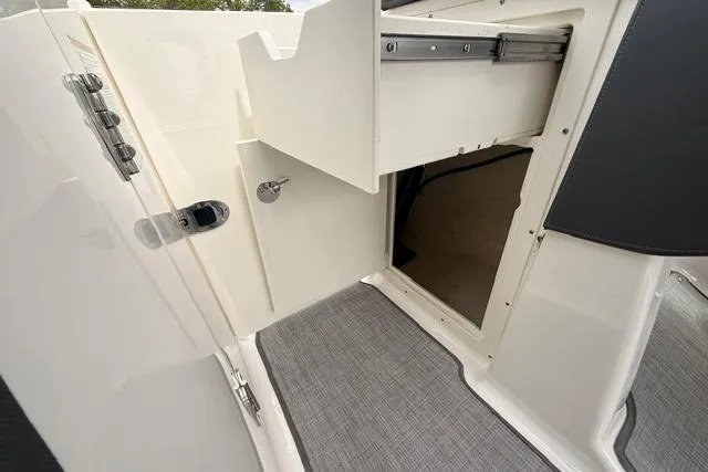 Slide: The Image of 2019 Chaparral 277 SSX boat interior storage compartment with open door and carpeted floor. - 18