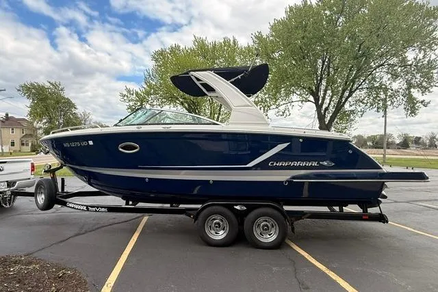 Slide: The Image of 2019 Chaparral 277 SSX boat on trailer, parked outdoors with trees in background. - 2