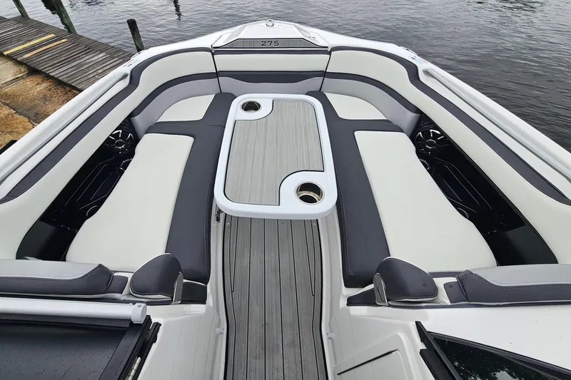 Slide: The Image of 2023 Yamaha Boats 275SDX interior with sleek seating and table, dockside view. - 25