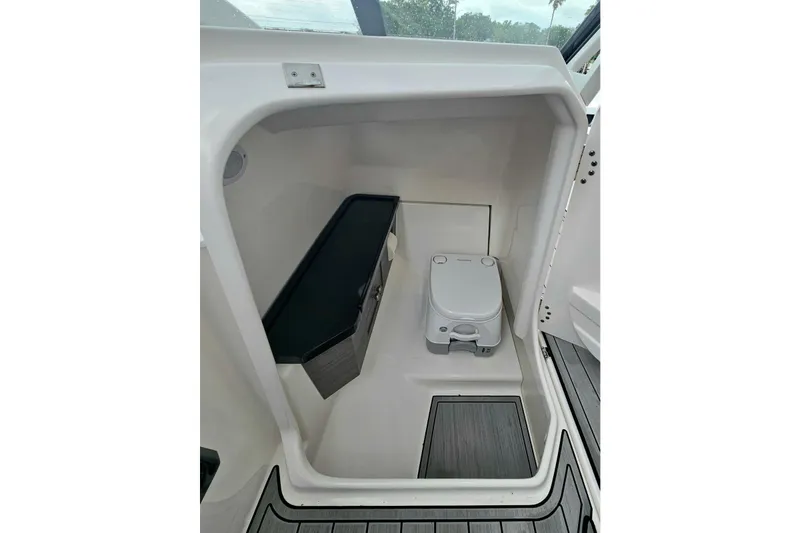 Slide: The Image of 2023 Yamaha Boats 275SDX interior cabin with compact toilet and storage area. - 26