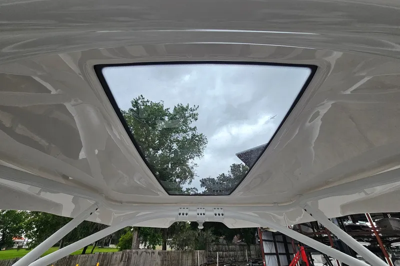 Slide: The Image of 2023 Yamaha Boats 275SDX sunroof view with trees and cloudy sky. - 29