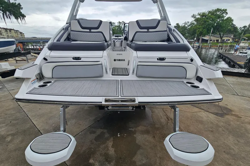 Slide: The Image of 2023 Yamaha Boats 275SDX rear view at dock, showcasing seating and swim platform. - 32