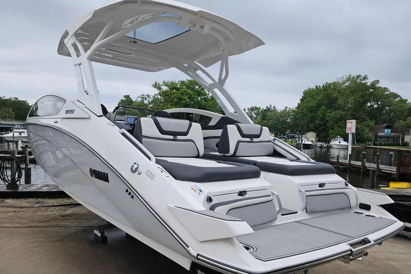 Slide: The Image of 2023 Yamaha Boats 275SDX, sleek white design, docked by a serene waterfront. - 4
