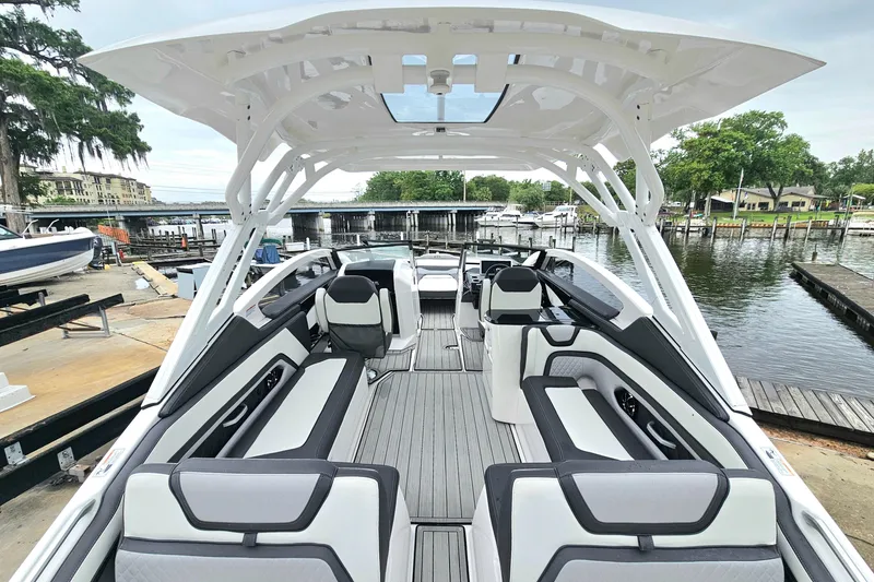 Slide: The Image of 2023 Yamaha Boats 275SDX interior, featuring sleek seating and modern design at a marina. - 9