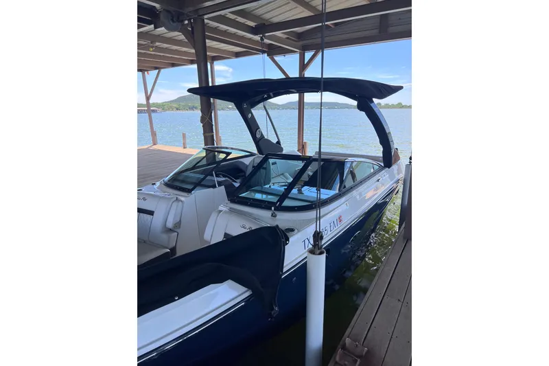 Slide: The Image of 2018 Sea Ray SLX 250 boat docked under a covered pier on a sunny day. - 2