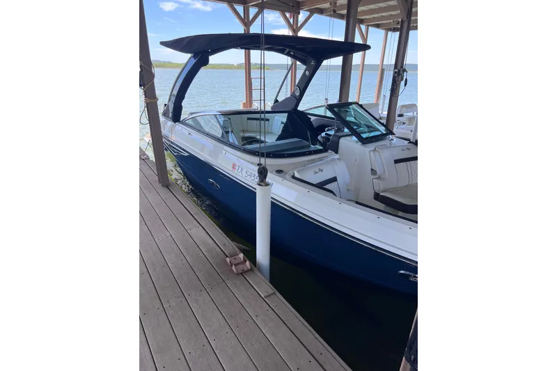 Slide: The Image of 2018 Sea Ray SLX 250 boat docked under a wooden shelter by the water. - 3