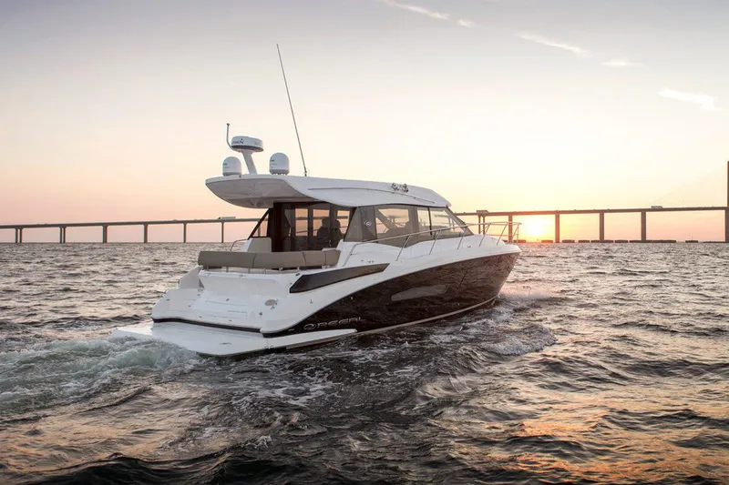 Slide: The Image of Manufacturer Provided Image: 2026 Regal 42 Grande Coupe yacht cruising at sunset near a bridge. - 2