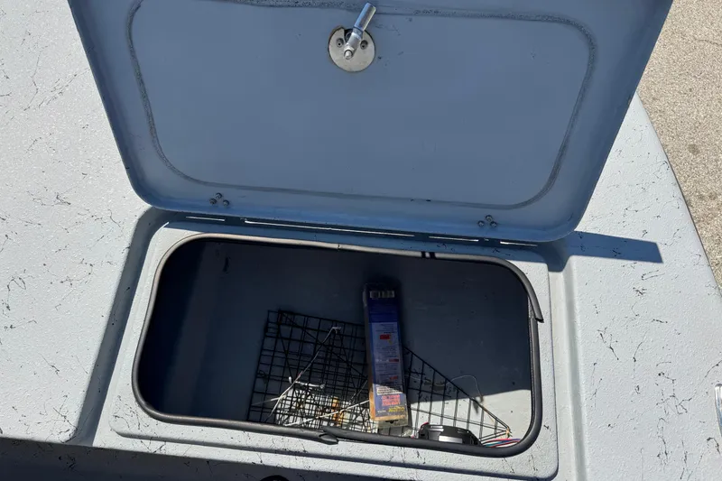 Slide: The Image of Open storage compartment on a 2016 El Pescador 24 CAT boat, showing interior contents. - 29
