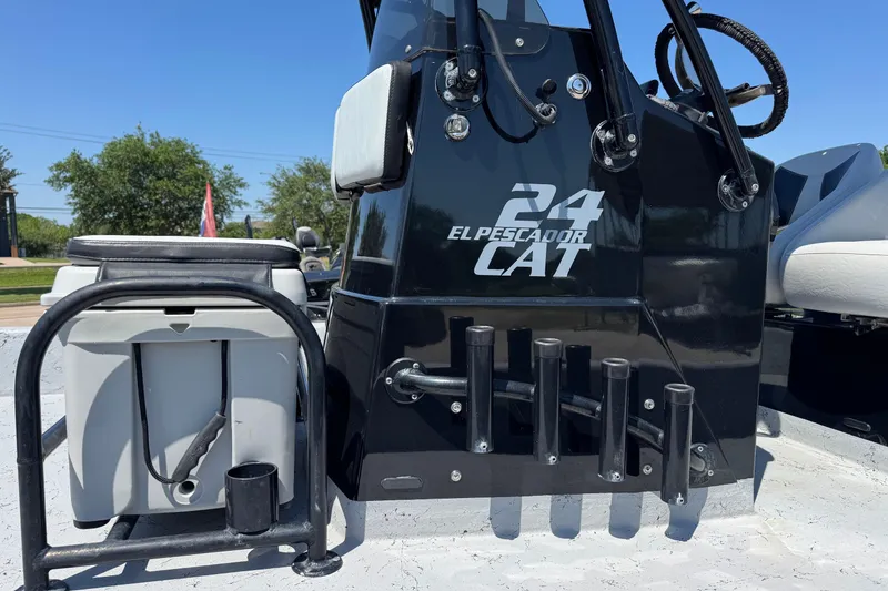 Slide: The Image of 2016 El Pescador 24 CAT boat console with rod holders and storage, under clear blue sky. - 6