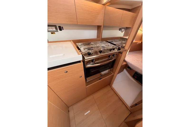 Slide: The Image of 2025 Jeanneau Sun Odyssey 350 yacht kitchen with modern appliances and wood cabinetry. - 60