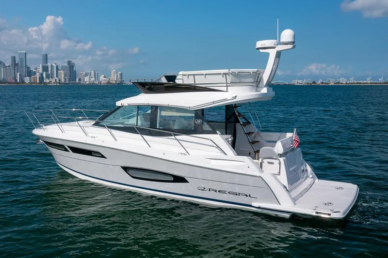 Slide: The Image of Manufacturer Provided Image: 2026 Regal 38 Fly yacht cruising on open water with city skyline backdrop. - 2