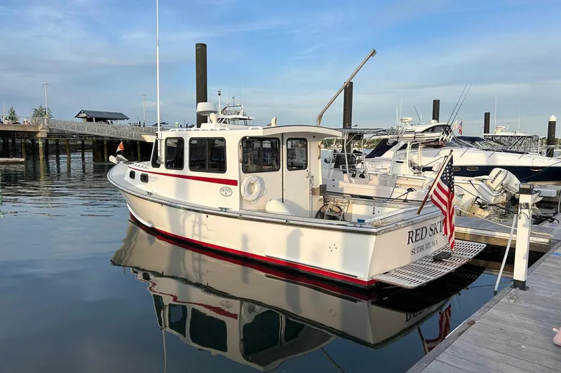 Slide: The Image of 1988 Duffy 31 Lobster Boat docked, reflecting on calm water, with American flag. - 2
