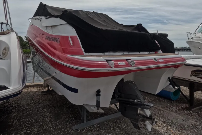 Slide: The Image of 2012 Four Winns V265 boat with red and white hull, covered and docked. - 15