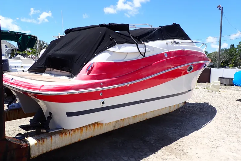 Slide: The Image of 2012 Four Winns V265 boat with red and white hull, covered and docked outdoors. - 2