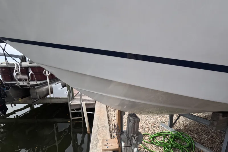 Slide: The Image of 2012 Four Winns V265 boat hull on dock with green hose nearby. - 23