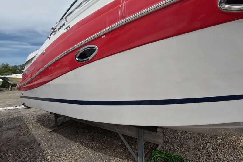 Slide: The Image of 2012 Four Winns V265 boat with red and white hull on a stand. - 24