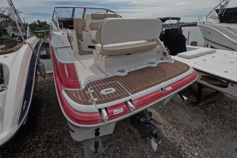 Slide: The Image of 2012 Four Winns V265 boat with red and white exterior, docked near water. - 3