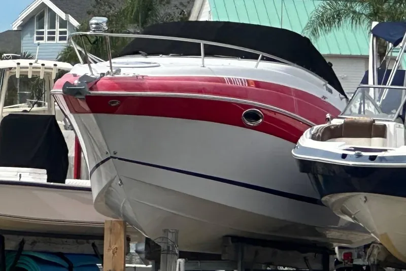 Slide: The Image of 2012 Four Winns V265 boat with red and white hull, docked near other vessels. - 4
