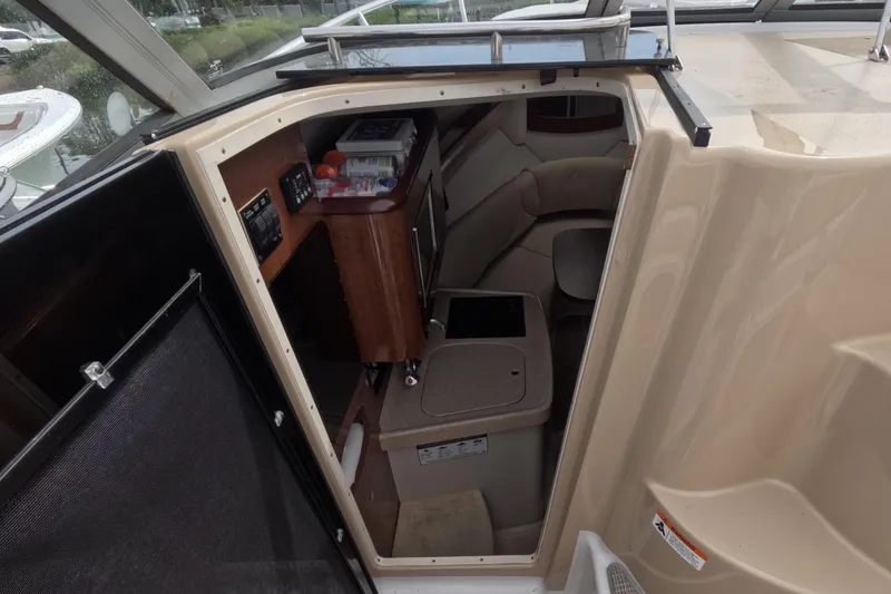 Slide: The Image of Interior cabin of 2012 Four Winns V265 boat, featuring seating and compact kitchenette. - 44