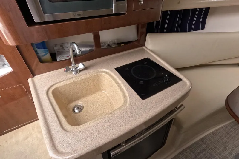Slide: The Image of 2012 Four Winns V265 boat interior with sink, stove, and microwave. - 53
