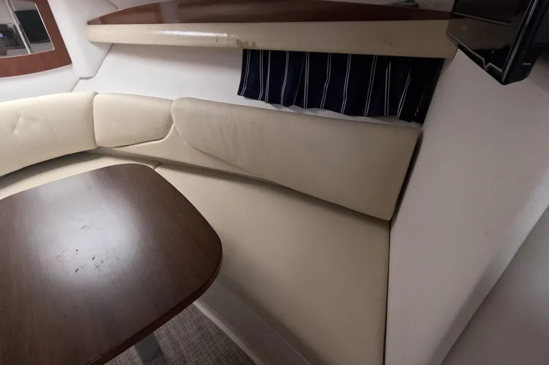 Slide: The Image of Interior of 2012 Four Winns V265 boat with beige seating and wooden table. - 54