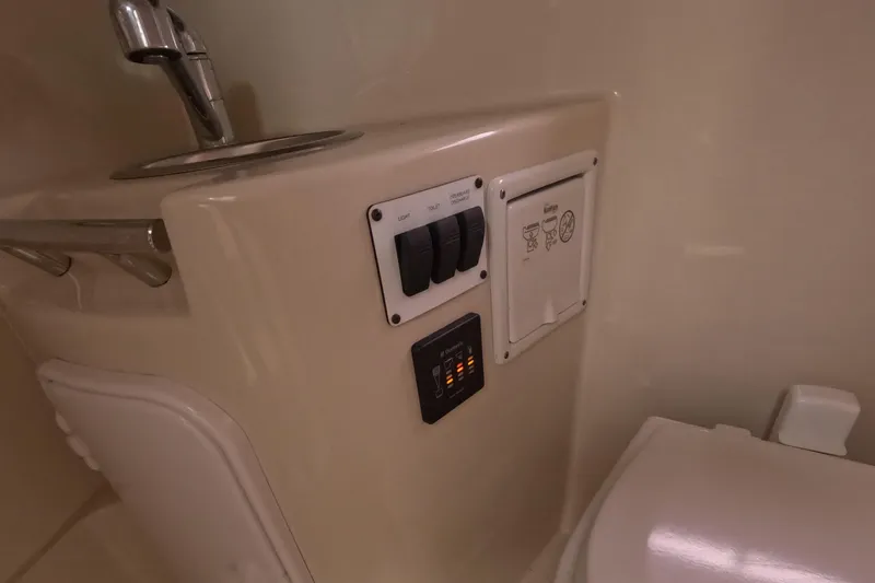 Slide: The Image of 2012 Four Winns V265 boat bathroom controls and fixtures, featuring switches and a faucet. - 63