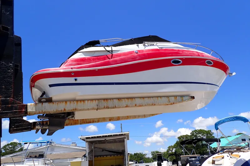 Slide: The Image of 2012 Four Winns V265 boat lifted on a dock under a clear blue sky. - 85