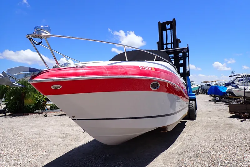 Slide: The Image of 2012 Four Winns V265 boat with red and white hull on dry dock under clear blue sky. - 86