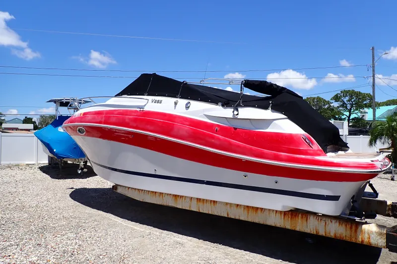 Slide: The Image of 2012 Four Winns V265 boat with red and white hull, covered and parked outdoors. - 87