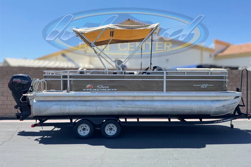 The Image of 2024 Sun Tracker SportFish 22 DLX pontoon boat with canopy on trailer. - 0