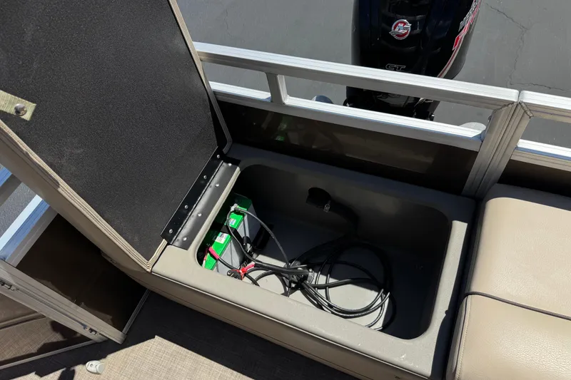 Slide: The Image of Open storage compartment on 2024 Sun Tracker SportFish 22 DLX boat, revealing battery and cables. - 22