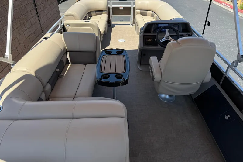 Slide: The Image of 2024 Sun Tracker SportFish 22 DLX pontoon boat interior with beige seating and steering console. - 24