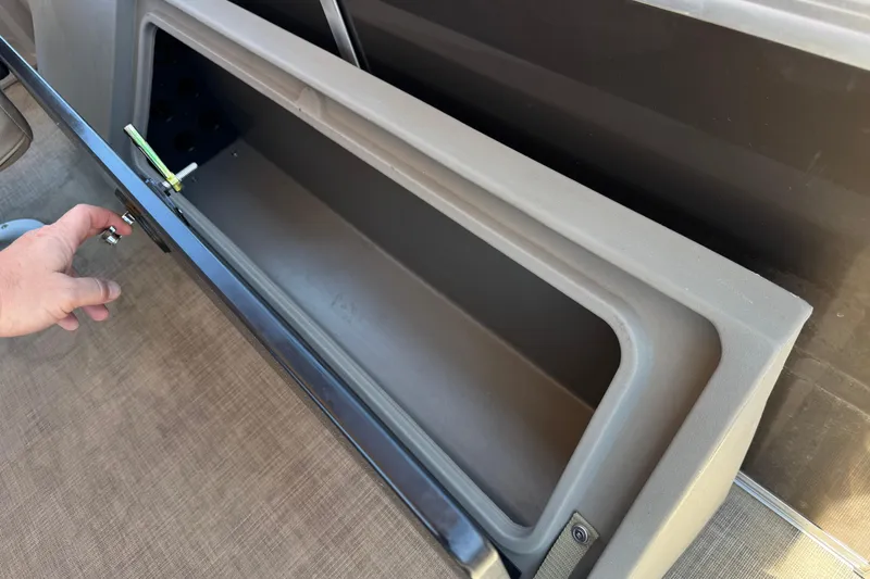 Slide: The Image of Storage compartment on 2024 Sun Tracker SportFish 22 DLX boat, open with hand accessing. - 26