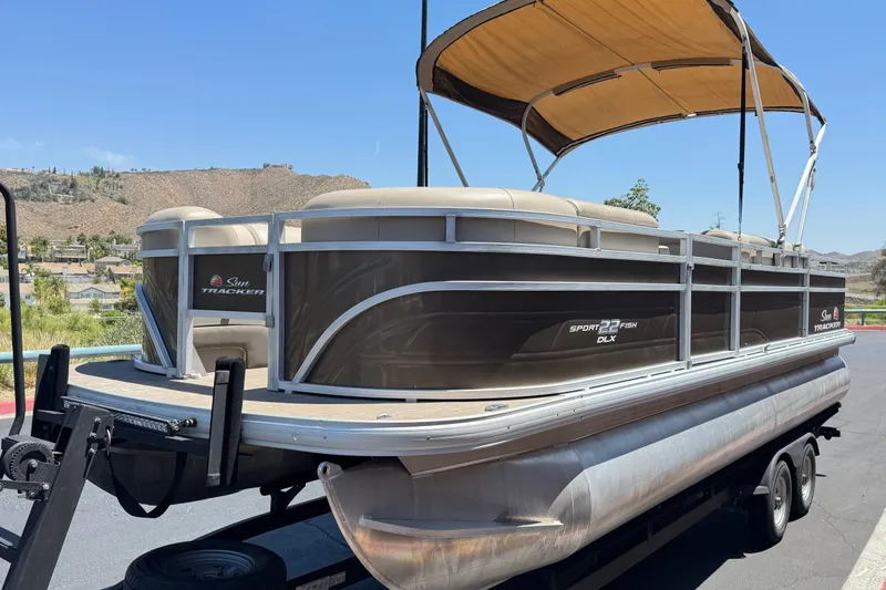 Slide: The Image of 2024 Sun Tracker SportFish 22 DLX pontoon boat with canopy on trailer. - 3