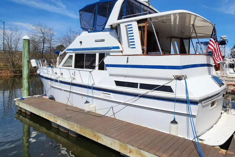 The Image of 1987 Jefferson 42 SE Sundeck Motor Yacht docked, featuring classic design and American flag. - 0