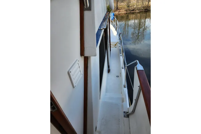 Slide: The Image of 1987 Jefferson 42 SE Sundeck Motor Yacht side deck view, featuring railing and water reflection. - 15