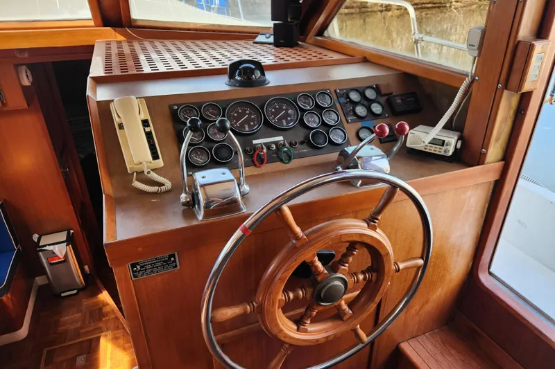 Slide: The Image of 1987 Jefferson 42 SE Sundeck Motor Yacht helm with classic wooden steering wheel and control panel. - 17