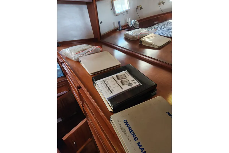 Slide: The Image of Interior of 1987 Jefferson 42 SE Sundeck Motor Yacht with manuals on wooden dresser. - 26