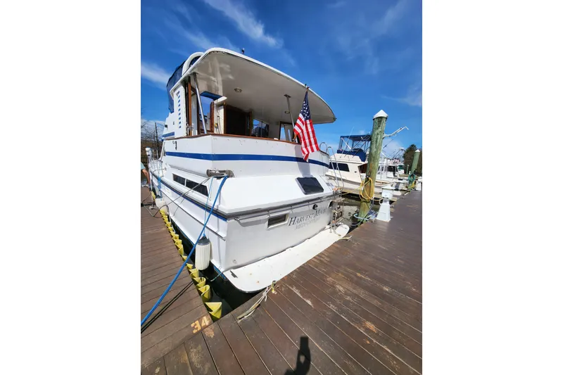 Slide: The Image of 1987 Jefferson 42 SE Sundeck Motor Yacht docked with American flag, clear sky background. - 3