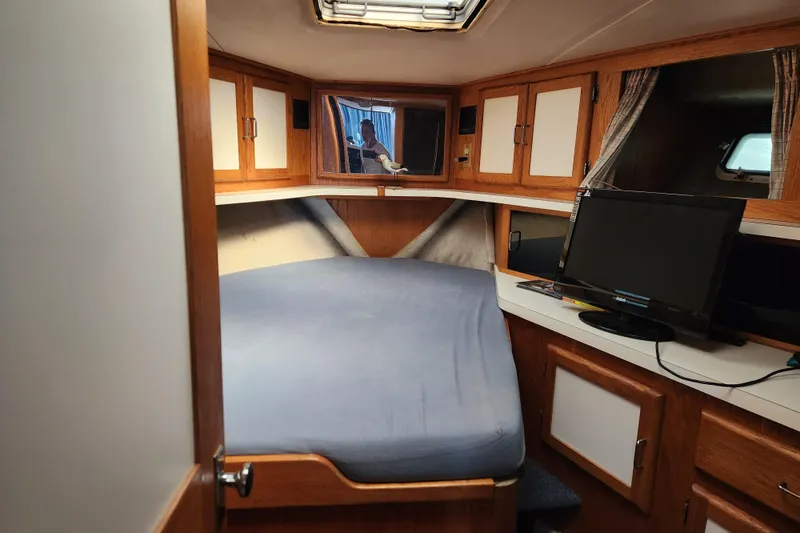 Slide: The Image of 1987 Luhrs 40 Convertible cabin interior with bed, cabinets, and TV. - 19