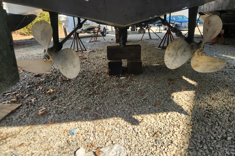 Slide: The Image of 1987 Luhrs 40 Convertible boat propellers on gravel, supported by blocks and stands. - 20