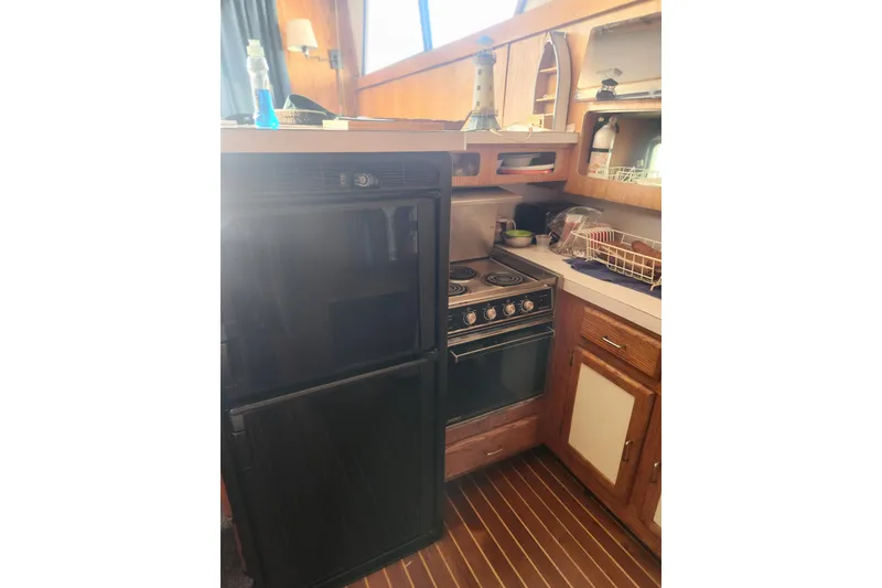 Slide: The Image of 1987 Luhrs 40 Convertible yacht kitchen with stove, refrigerator, and wooden cabinetry. - 25