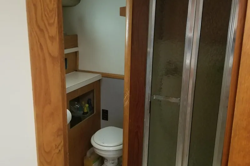 Slide: The Image of 1987 Luhrs 40 Convertible bathroom with shower and toilet, featuring wooden cabinetry. - 39