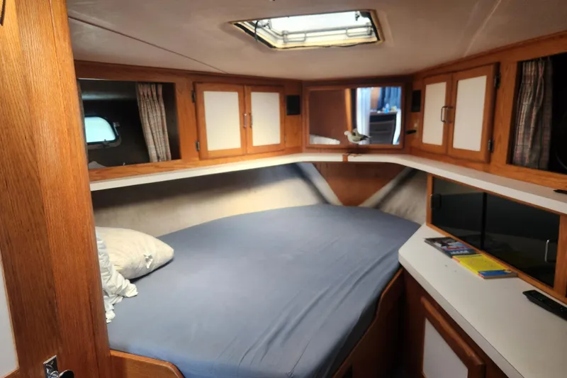 Slide: The Image of 1987 Luhrs 40 Convertible cabin interior with bed, wooden cabinets, and skylight. - 8