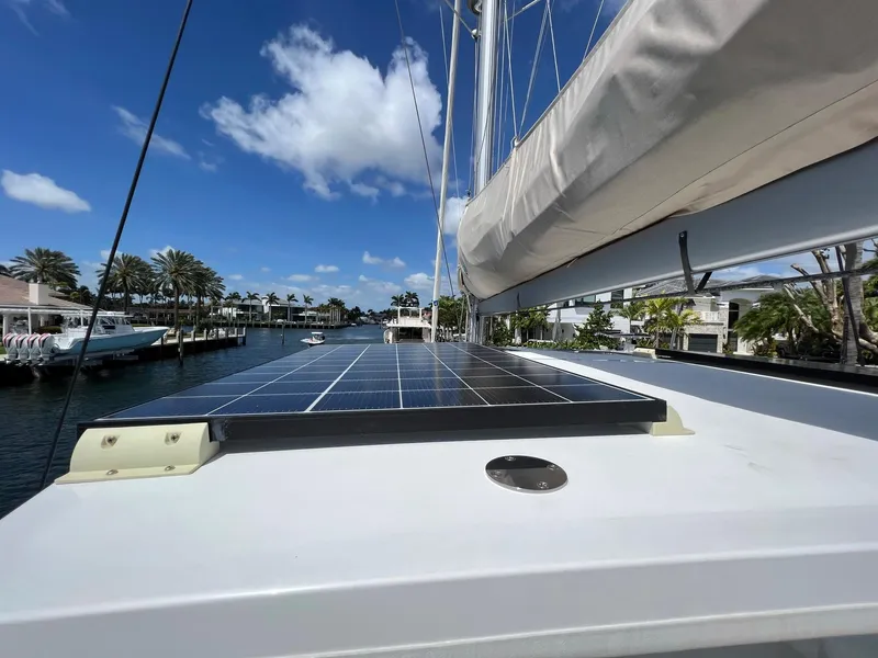 Slide: The Image of 2022 Lagoon 46 catamaran with solar panels on deck, sunny harbor background. - 13