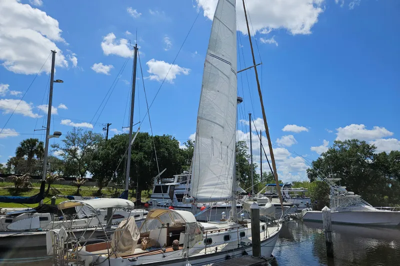 Slide: The Image of 1988 Cape Dory 38 sailboat docked under a clear blue sky with fluffy clouds. - 12