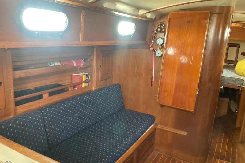 Slide: The Image of Interior of 1988 Cape Dory 36 sailboat with wooden cabinetry and blue cushioned seating. - 14