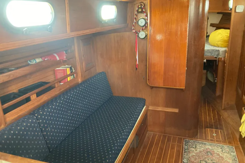 Slide: The Image of Interior of 1988 Cape Dory 36 sailboat with wooden paneling and blue cushioned seating. - 15